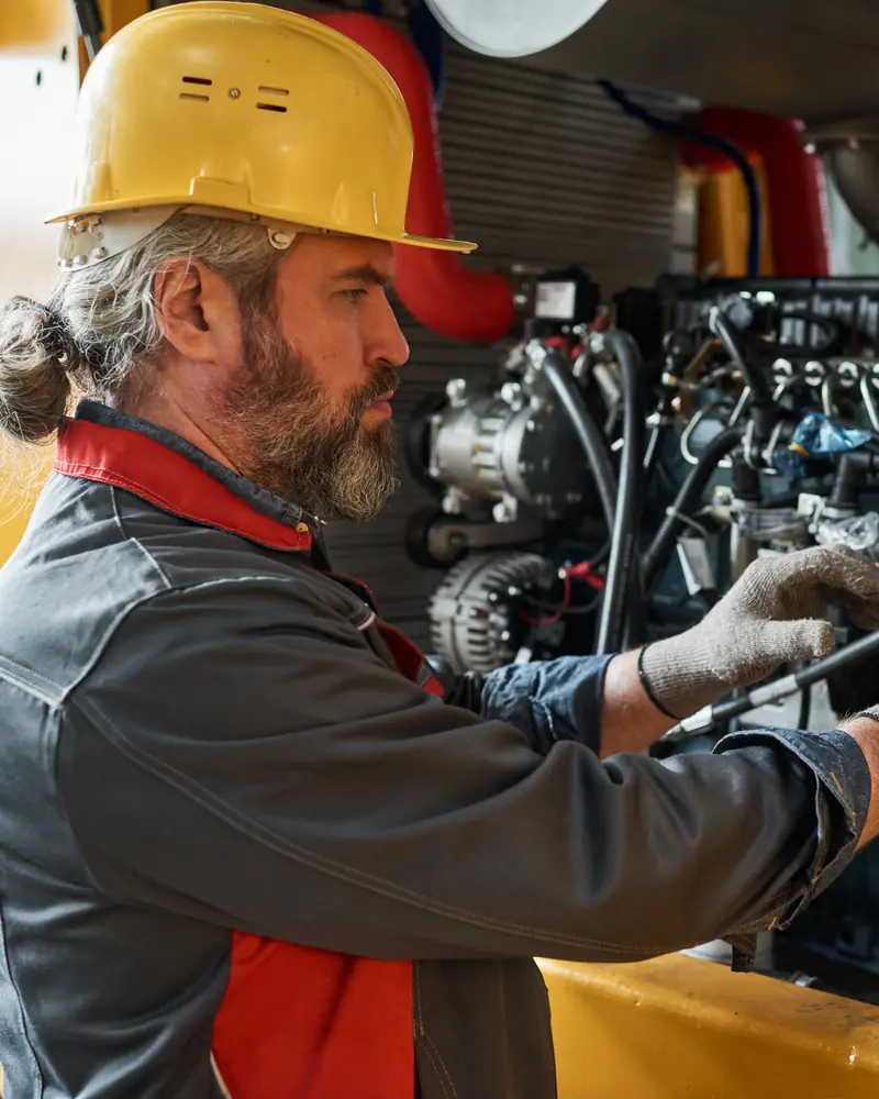 Engineer in a hard hat servicing an industrial diesel engine