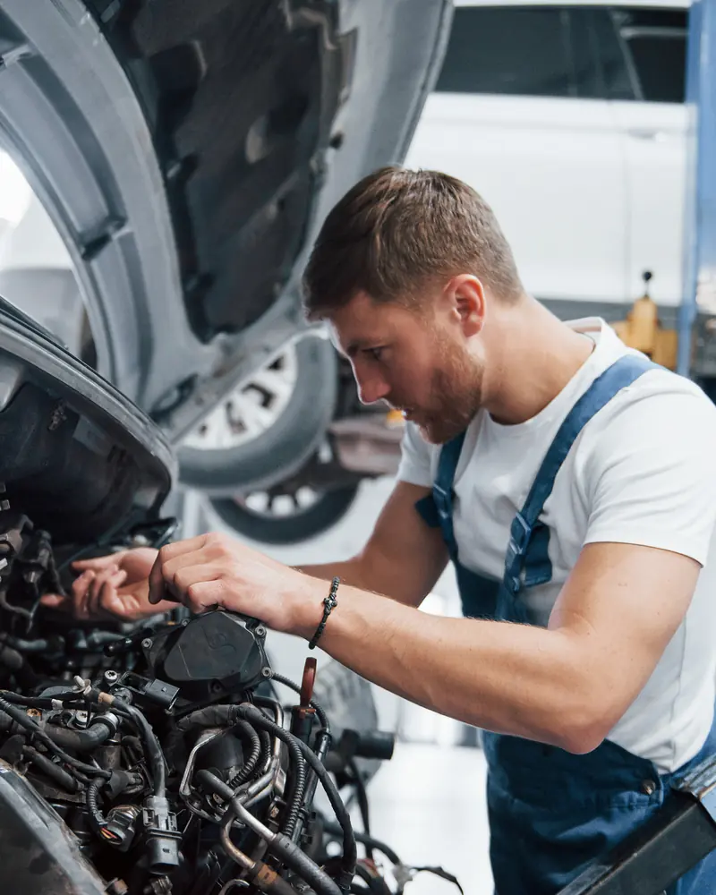 Workshop engineer working on a diesel engine on a lift