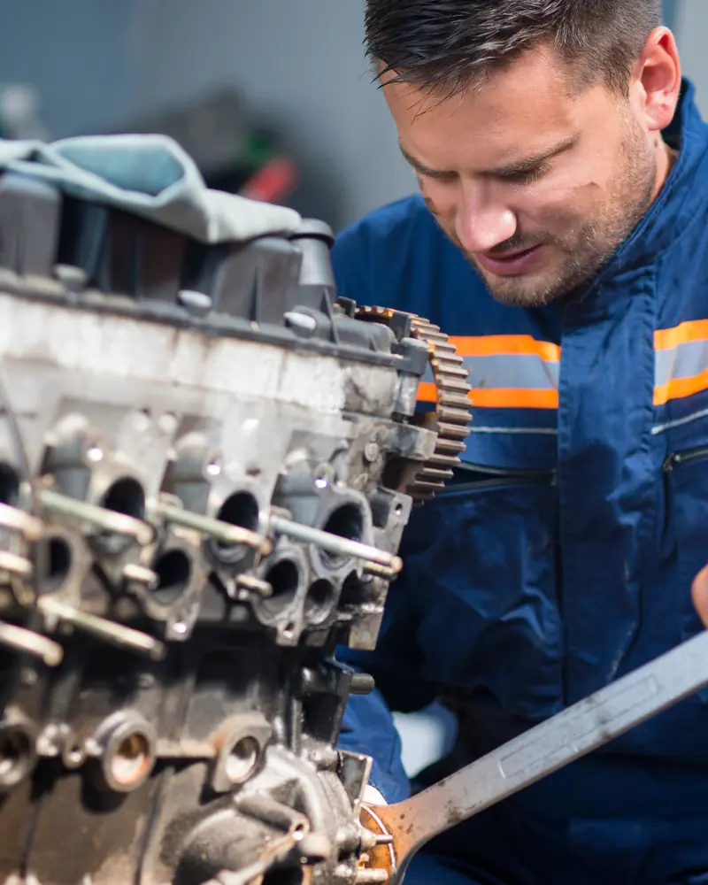 Engineer stripping a diesel cylinder head during engine reconditioning