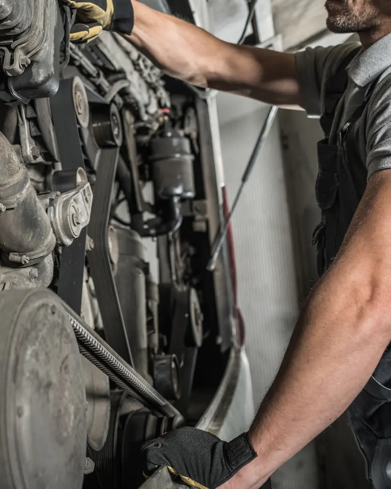 Engineer checking belts and components on a commercial diesel engine